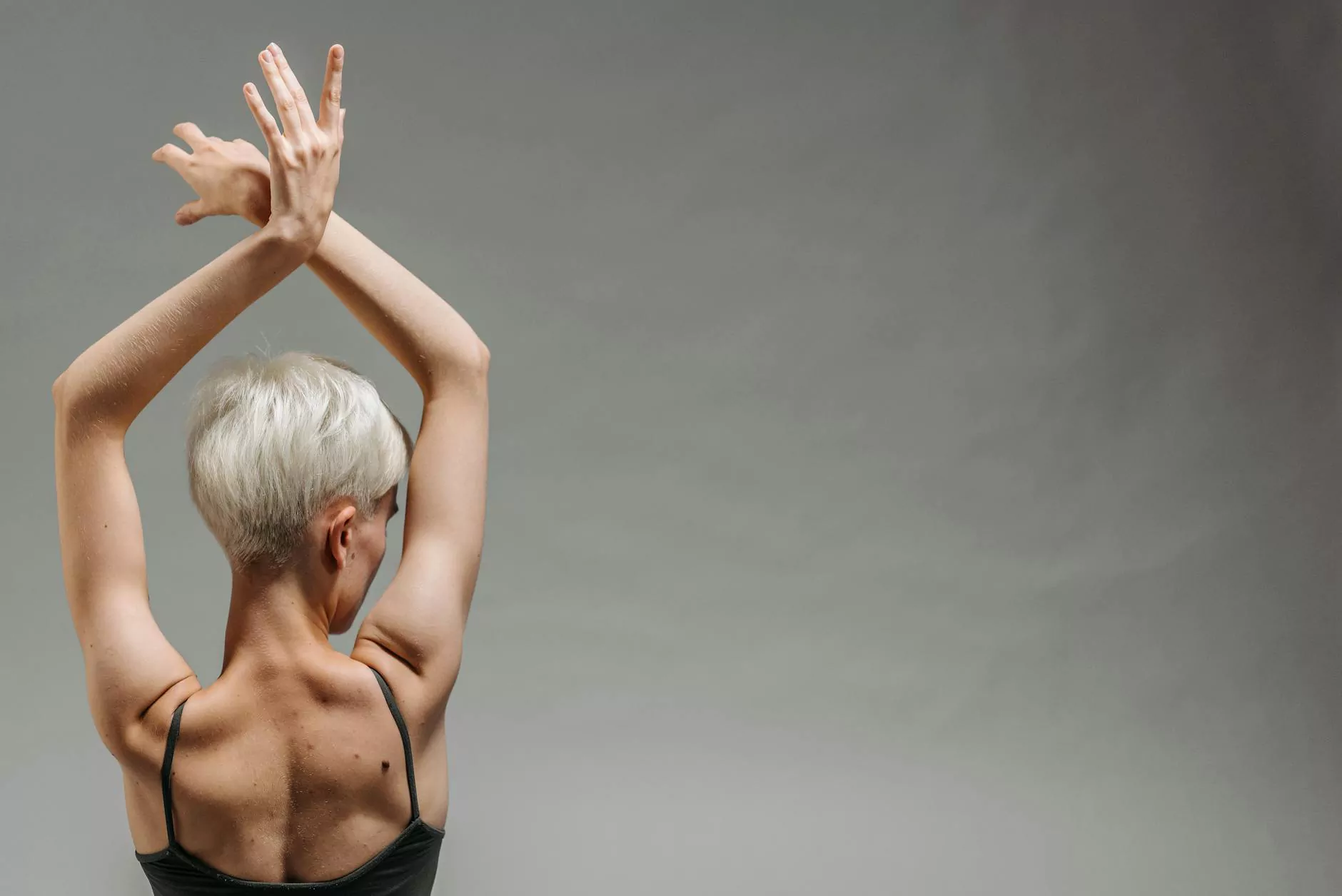 A person with arms raised against a quiet gray background